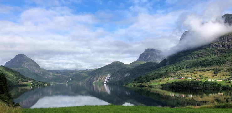 Ein trong fjord mellom fjellsider og blå himmel