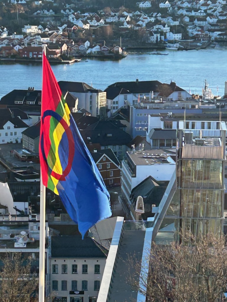 Flaggstang med det samiske flagget og utsikt over byen