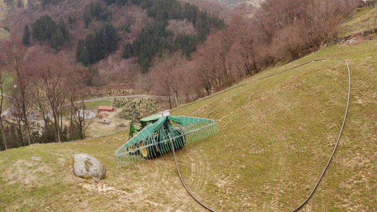 Skog, grøn traktor, gjødselspreiing med slange.