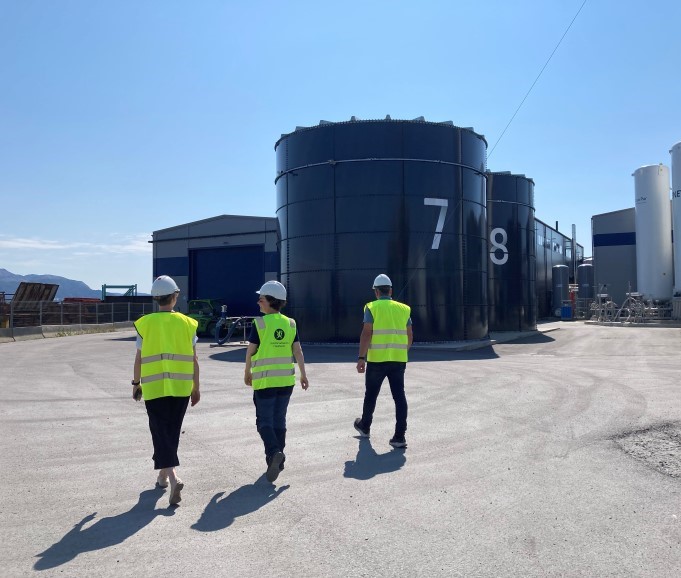 tre personar i gule refleksvestar med hjelm på eit industriområde