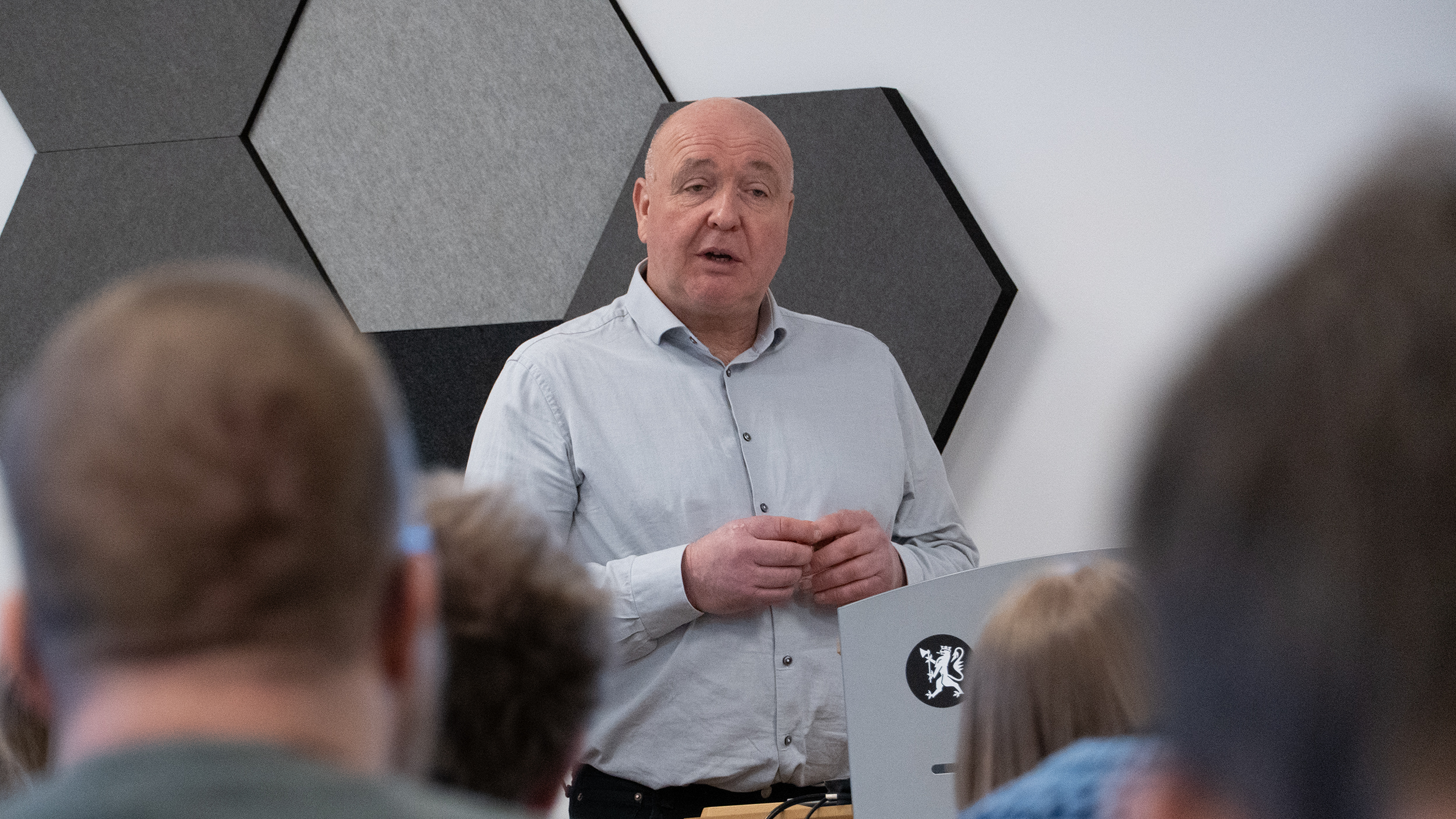 Mann står bak talestol og snakker til publikum.
