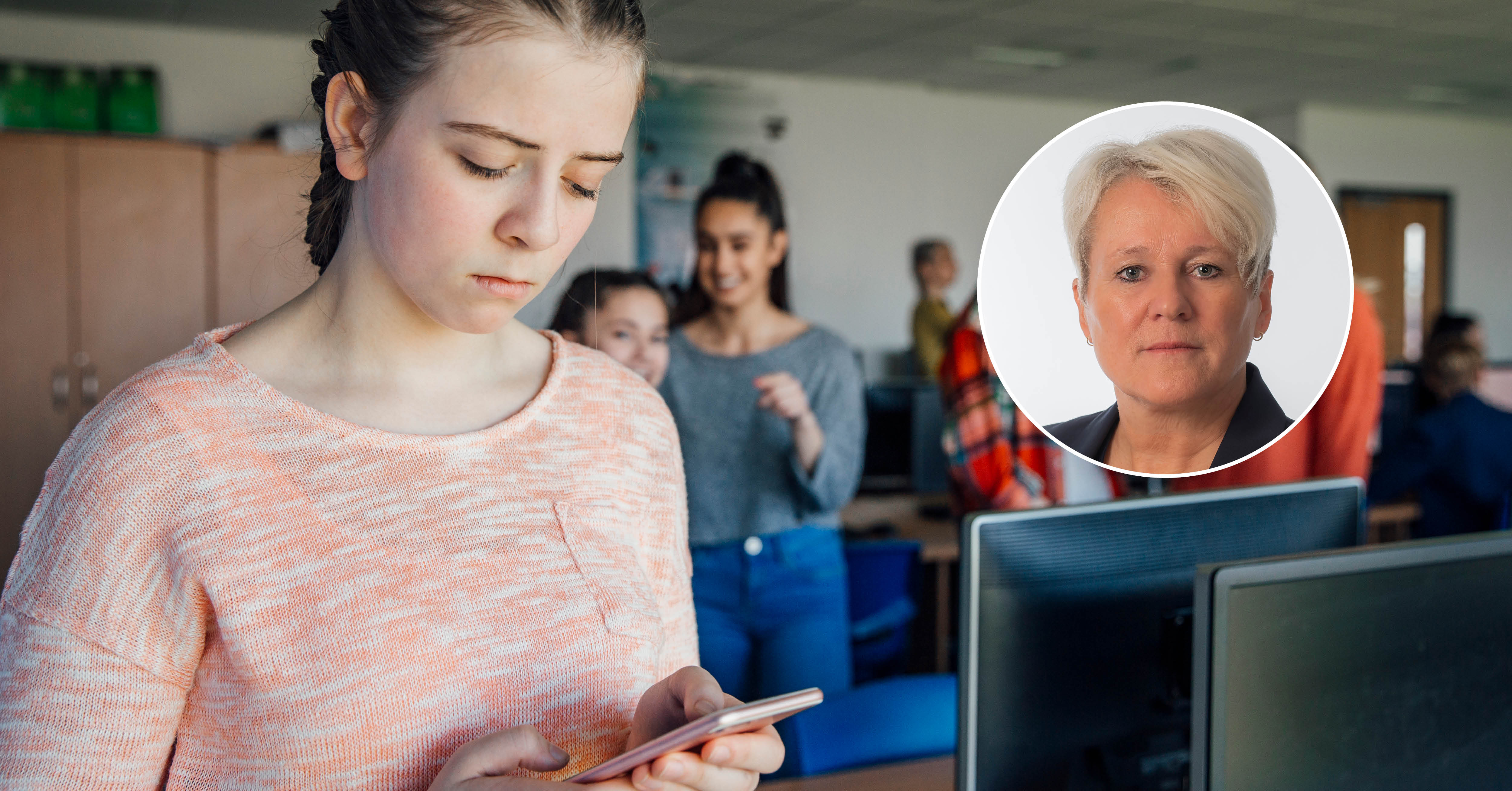 Bilde av ei jente som ser trist ned i mobilen mens klassevenninner står rundt og ler