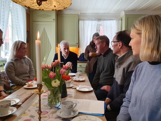Statsminister Jonas Gahr Støre i samtale med en gruppe mennesker rundt et bord.