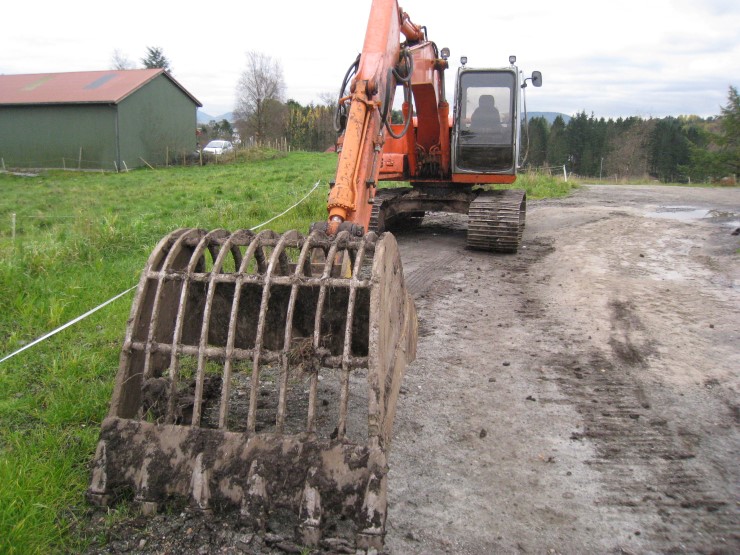 Gravemaskin, grønt gras, fjøs, 