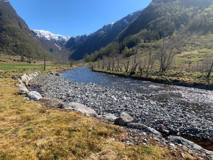 Ei elv i ein dal med fjelltoppar i bakgrunnen