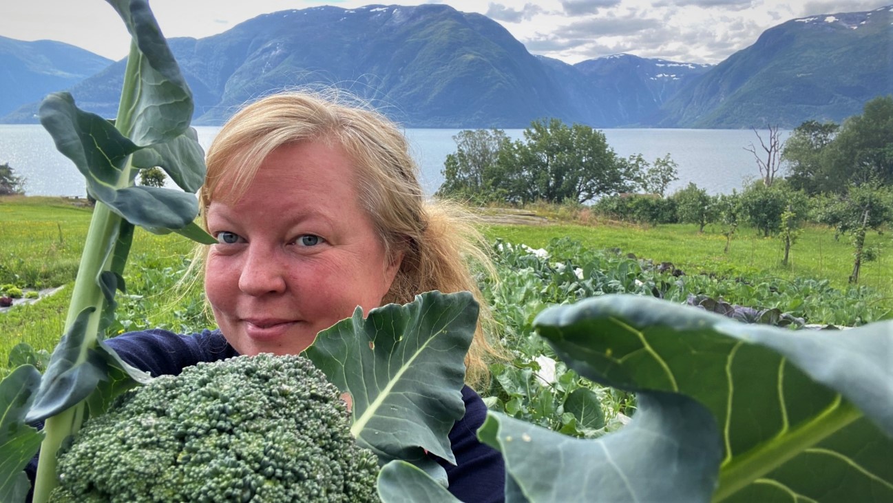 Kvinne med brokkoli i forgrunnen og fjordlandskap i bakgrunnen