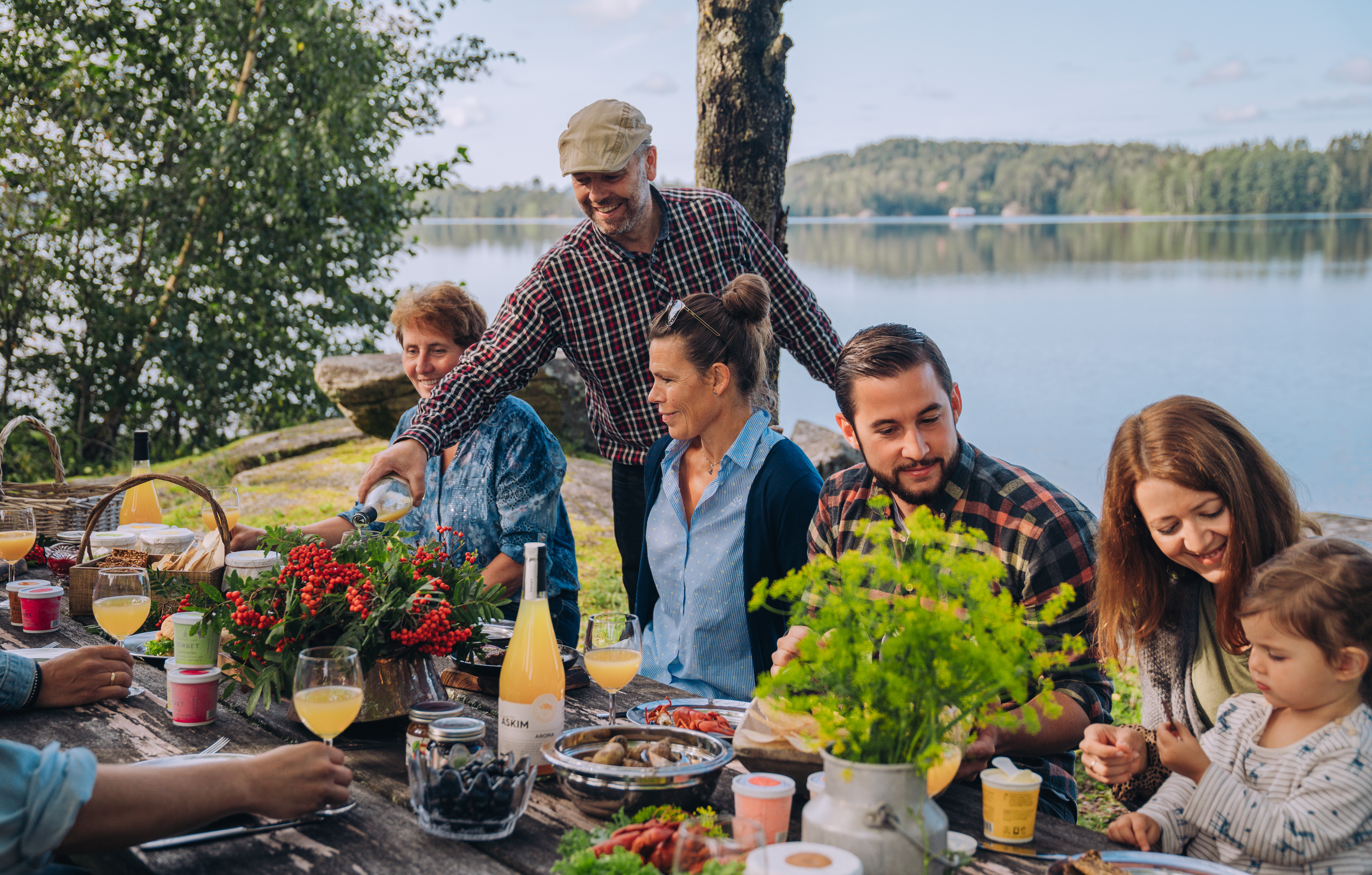 Bilde som viser mennesker rundt et bord, mat og drikke, natur