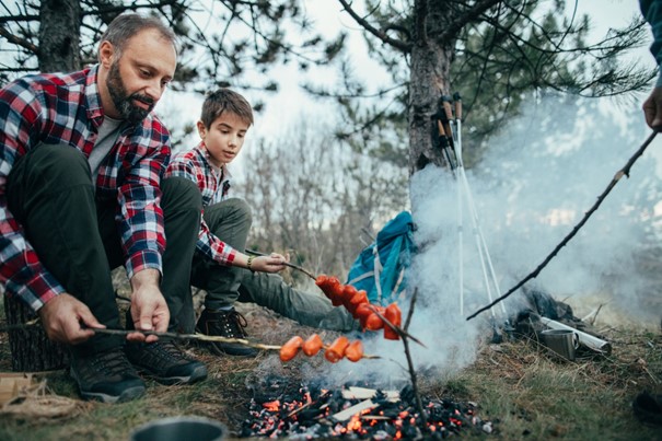 Folk griller mat på et bål i skogen