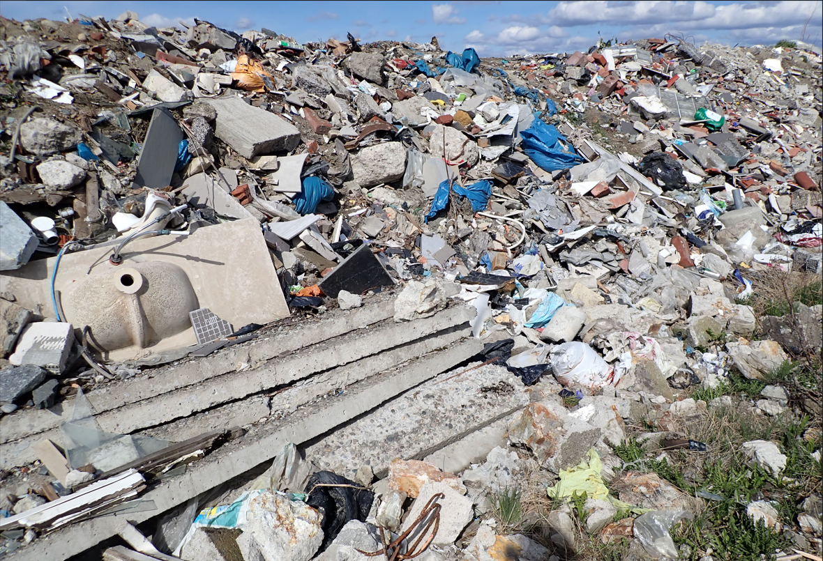 Diverse deponert avfall som betong, plastikk og lecablokker på et avfallsdeponi.
