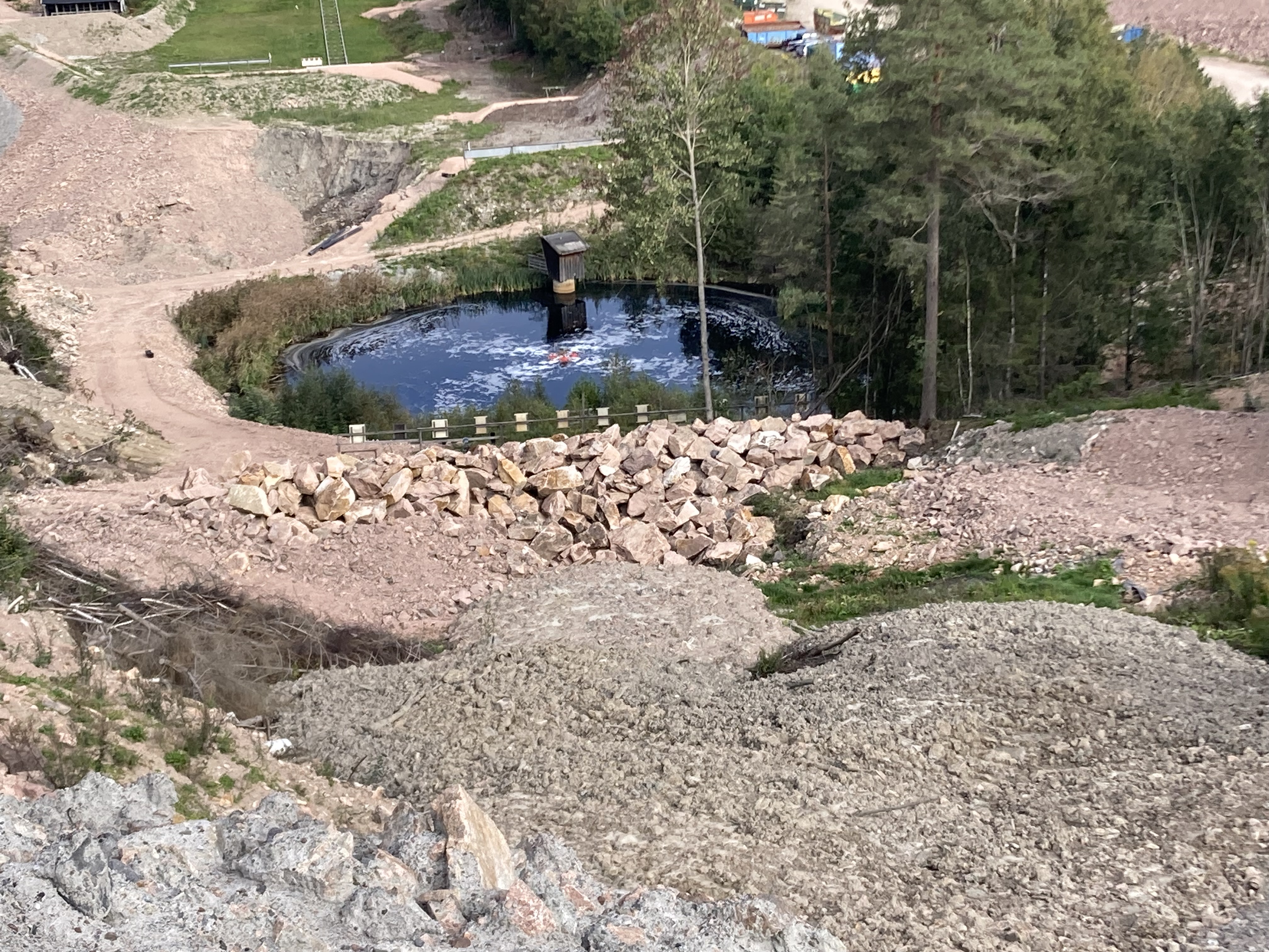 Bilde av en sigevannsdam på et avfallsdeponi. Ligger jord- og steinmasser på anleggsområdet, men og et lite grøntområdet rundt selve sigevannsdammen.