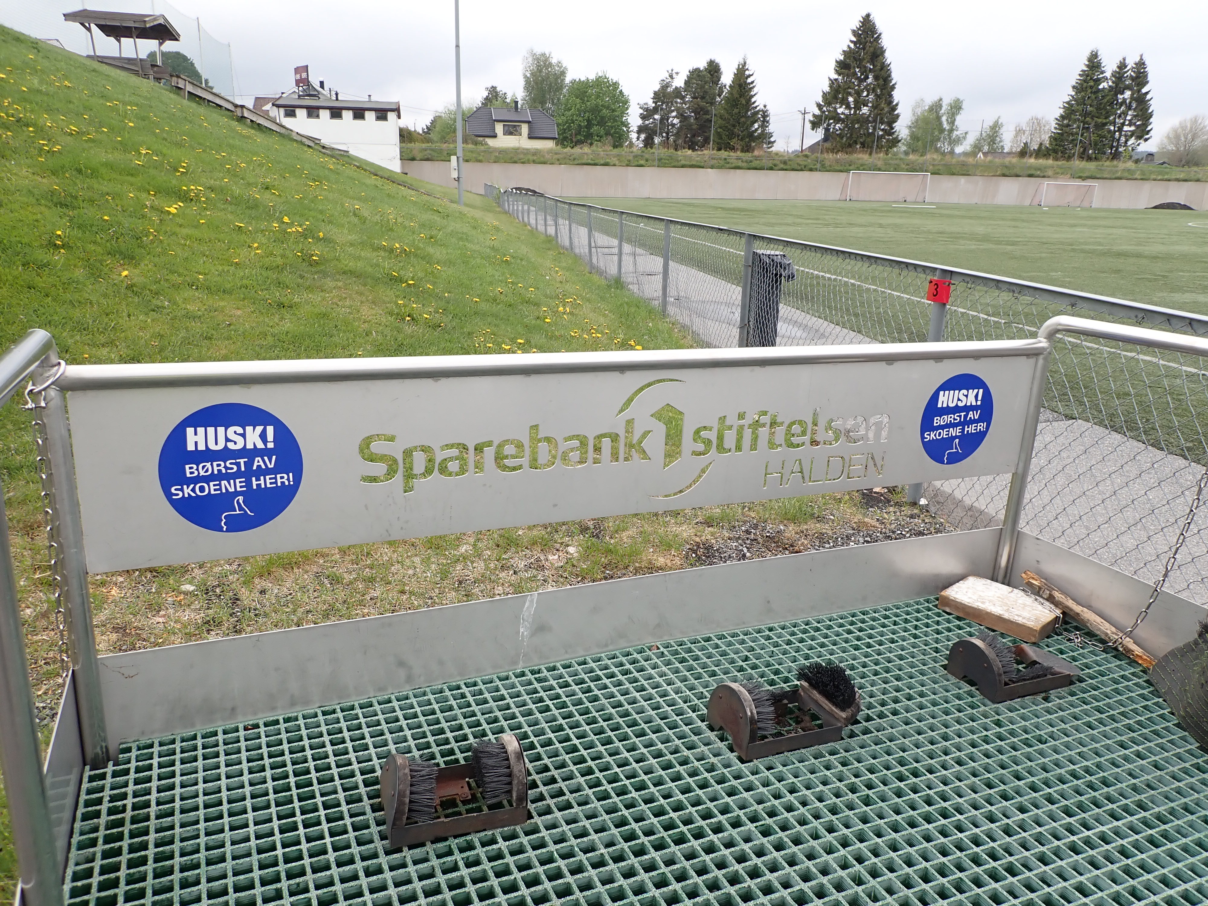 Stasjon for å børste gummigraunlat av skoene ved fotballbane.