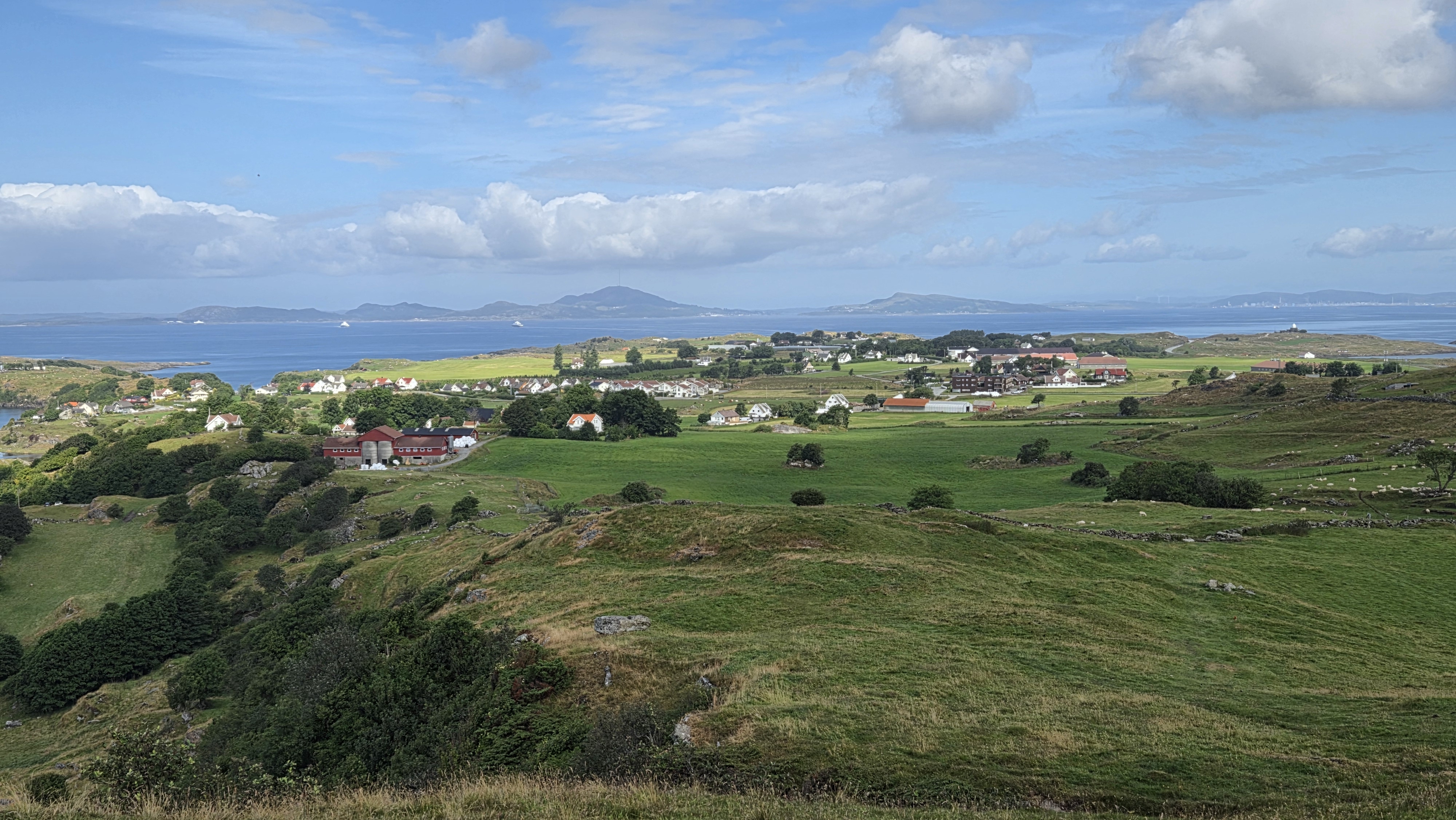 Utsikt fra toppen av Bø på Rennesøy ut mot innmarksbeite og bebyggelse.