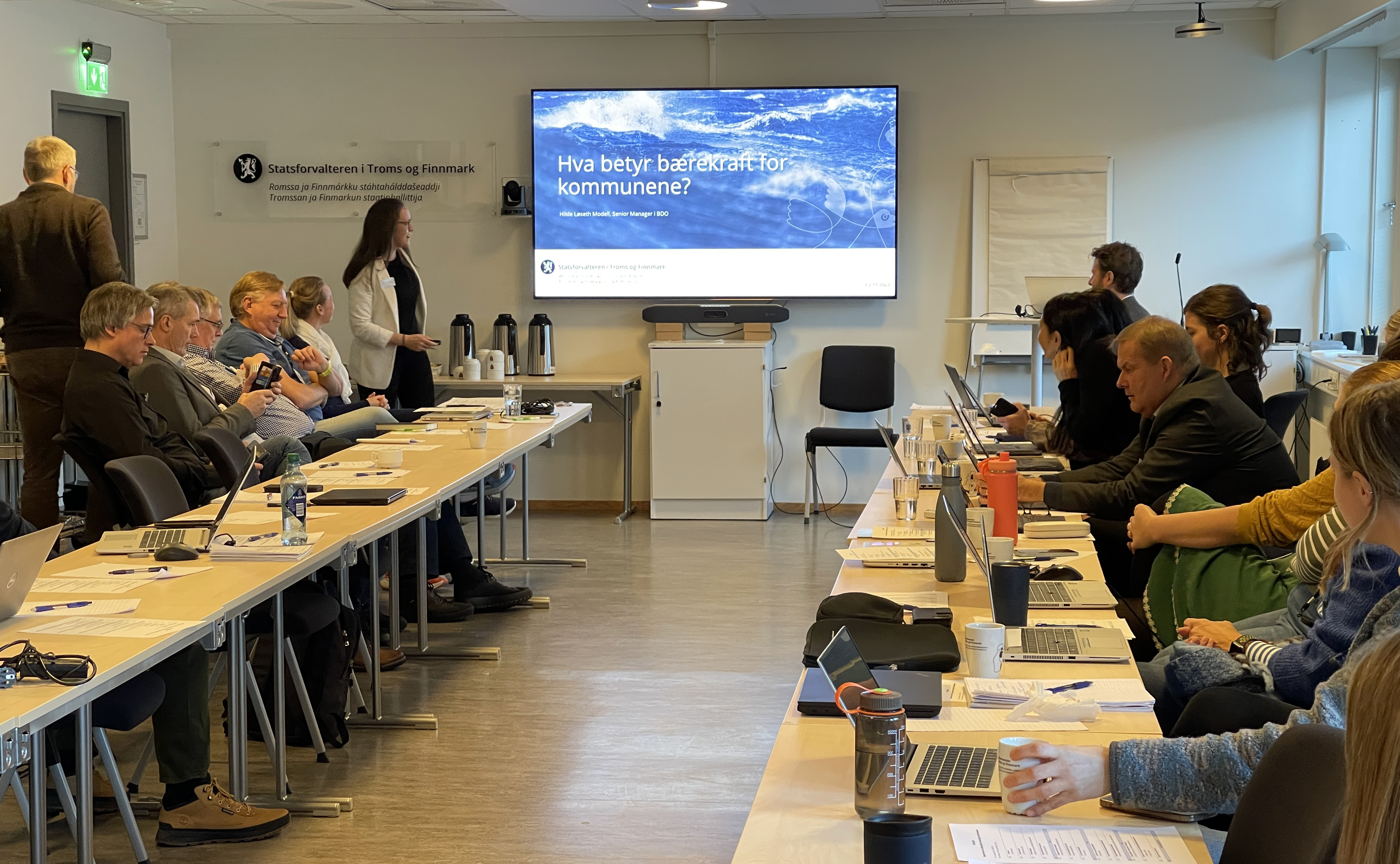 Mennesker i møterom med en presentasjon på storskjerm