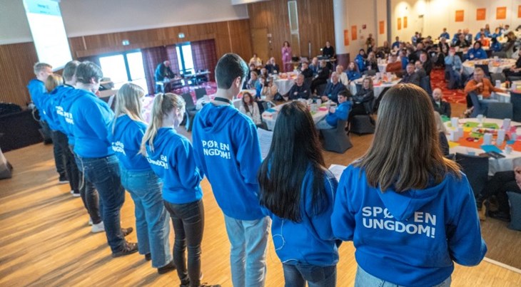 Ungdommer med hettegenser med teksten spør en ungdom på scenen på møte med kommunene i Troms og Finnmark