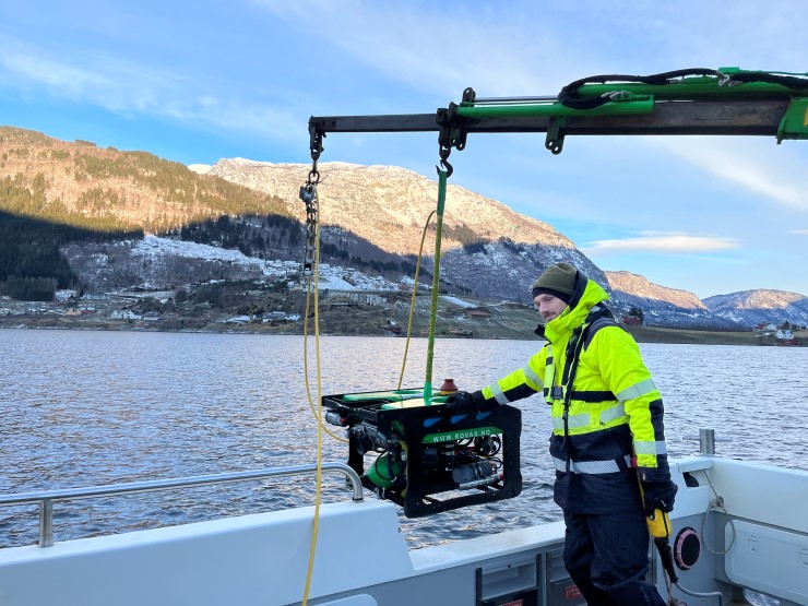 en person på båt med eit undervassdrone i vinterlandskap
