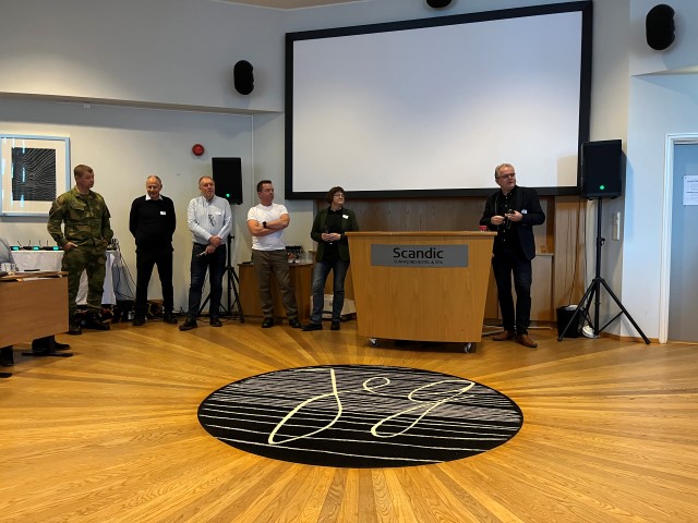 6 personer som diskuterer, skjerm, mikrofon 