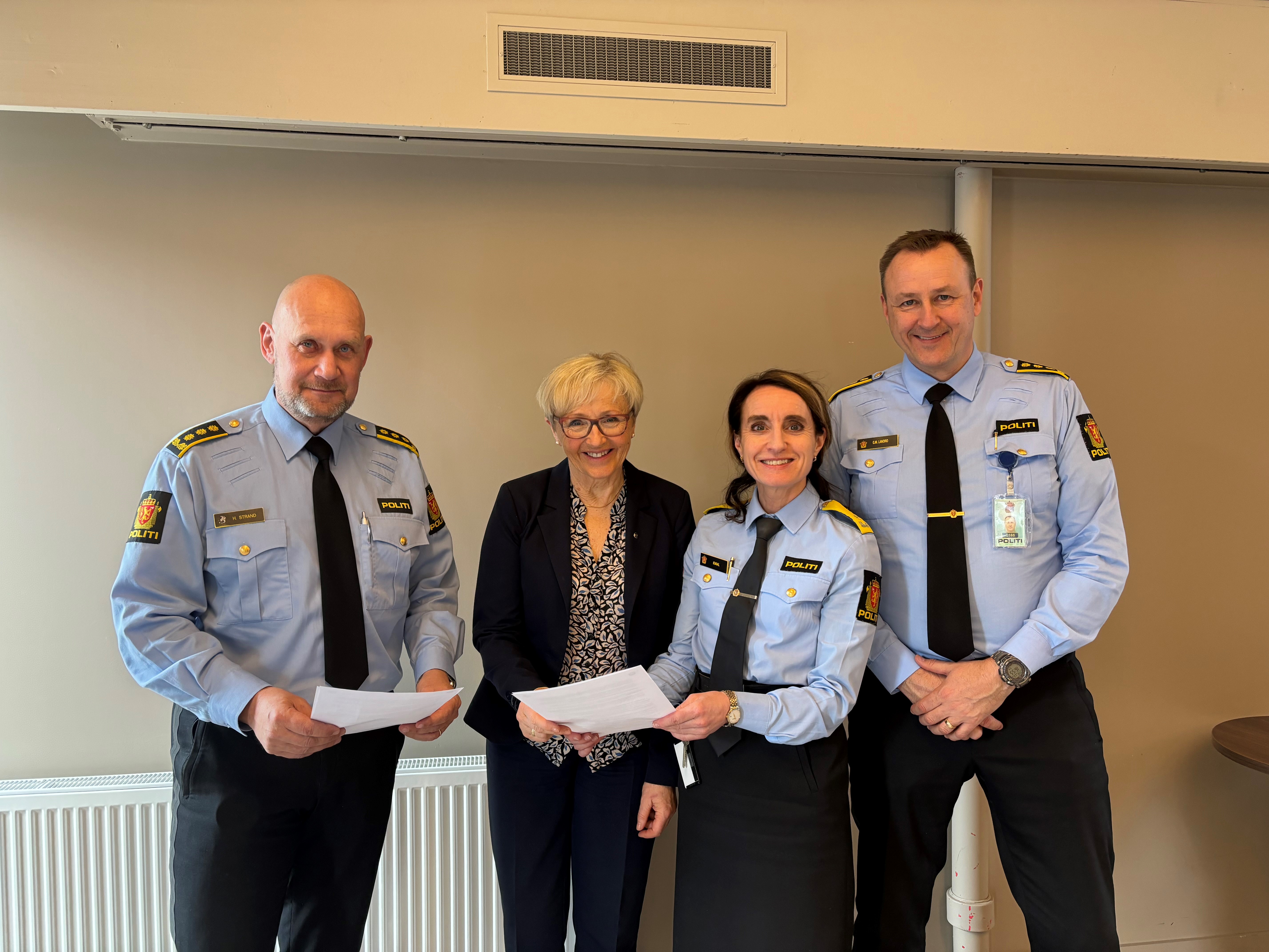 To kvinnar og to menn står oppstilt å ser på fotografen med nokre papir i henda. 