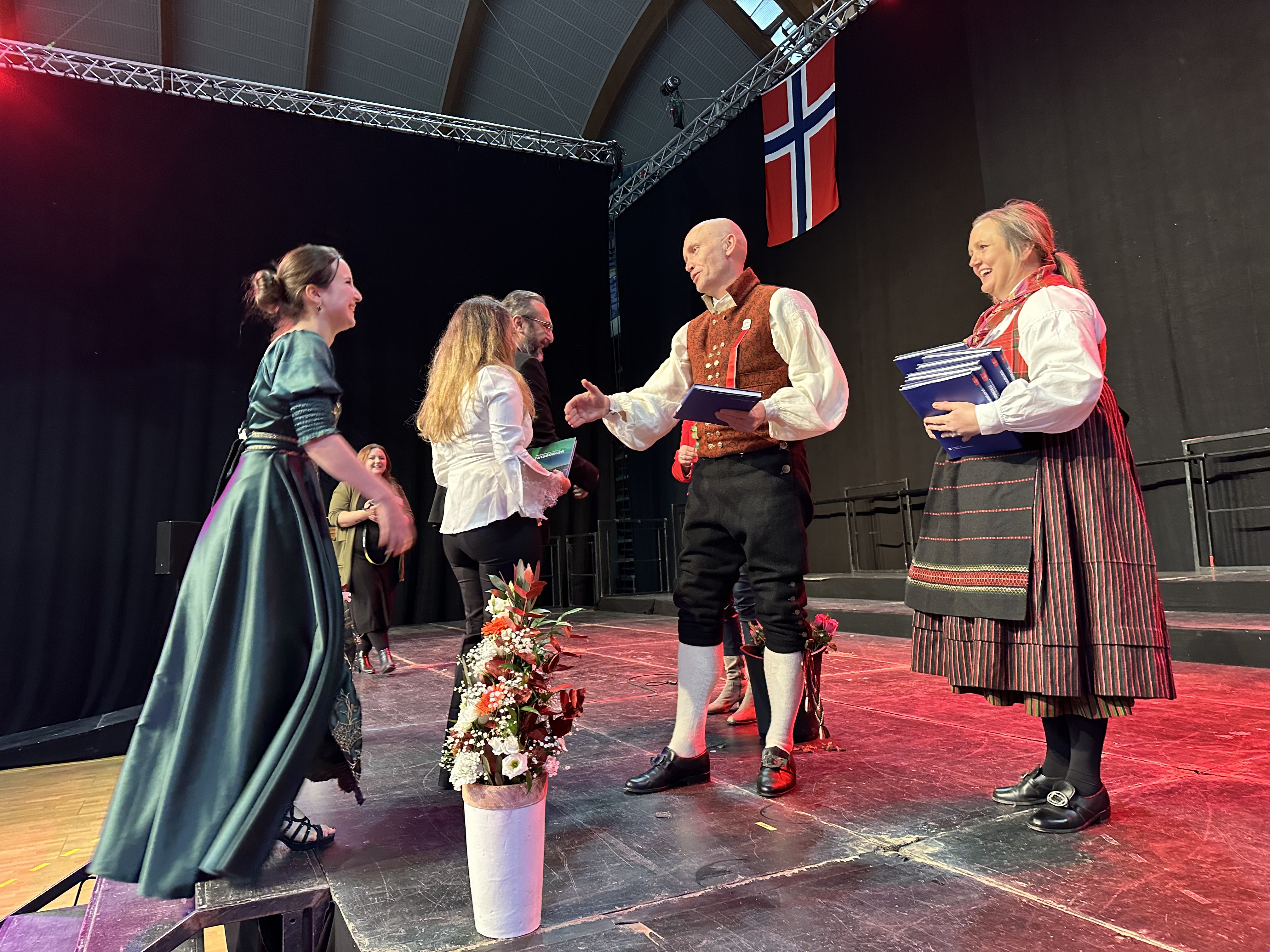 Statsborgere kommer på scenen under seremoni, og statsforvalter håndhilser.