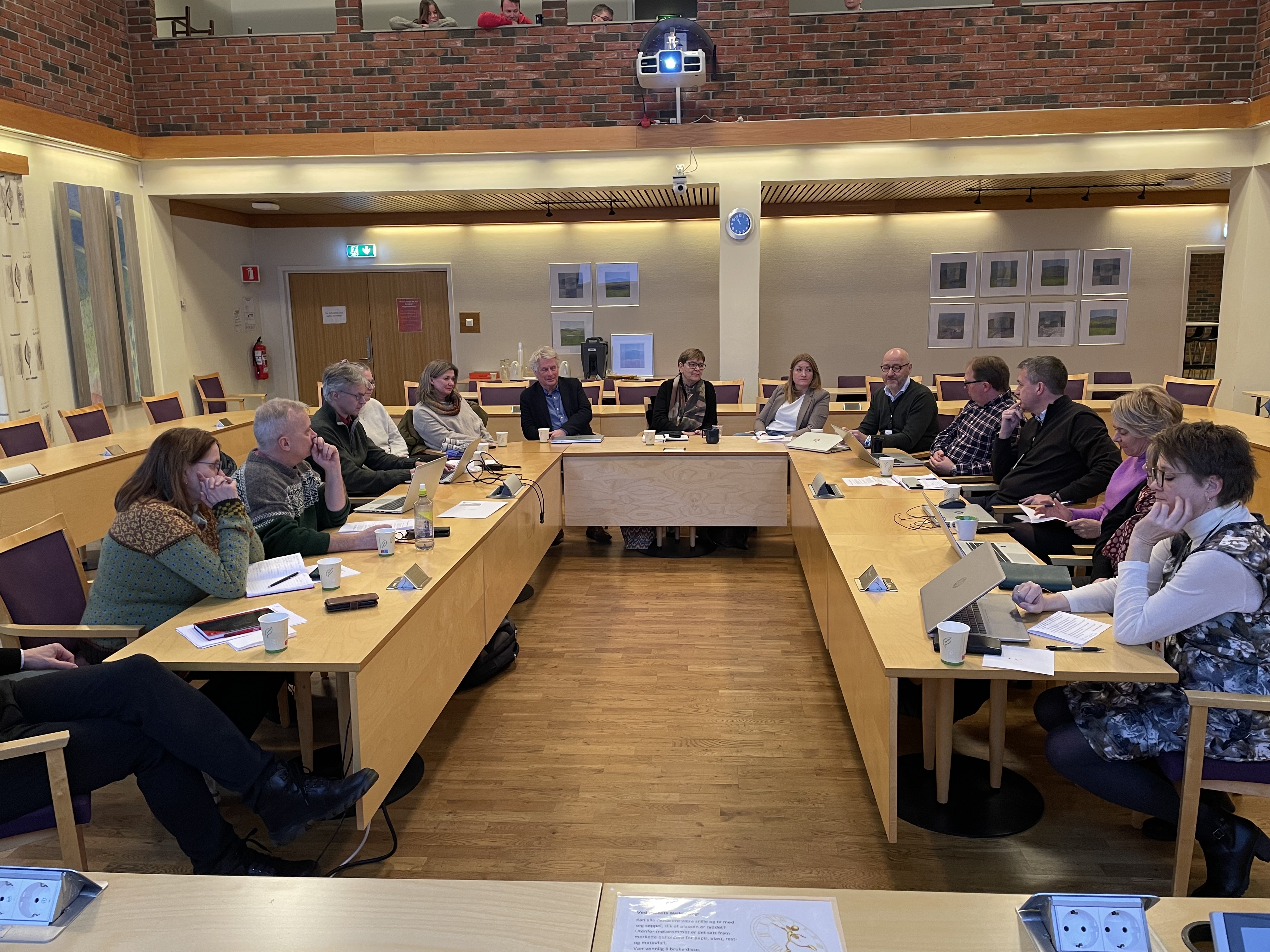 Folk sitter rundt et bord i et møterom